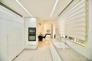 a white kitchen with a sink and a stove at אירופה בוטיק כנרת - דירת 4 חדרי שינה עם נוף לכנרת in Tiberias