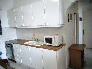 a kitchen with white cabinets and a sink and a microwave at Anastasia in Paralía Akrátas