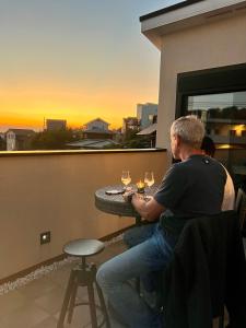 a man sitting at a table on a balcony with wine glasses at Cielito Hayama in Hayama