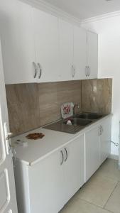 a white kitchen with a sink and white cabinets at Dhoma Pushimi Tale Beach in Lezhë