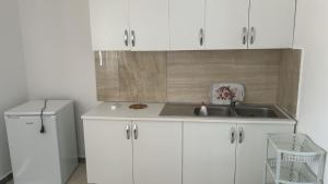 a kitchen with white cabinets and a sink and a refrigerator at Dhoma Pushimi Tale Beach in Lezhë