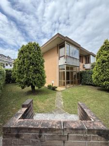 a large house with a tree in the yard at Giardinetto Apartment in Lido di Jesolo
