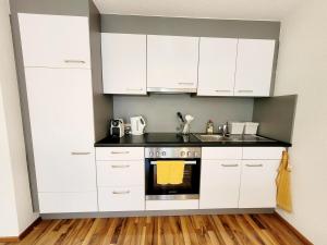a kitchen with white cabinets and a stove at Top2 Apartmenthaus Sonnenschein in Dornbirn