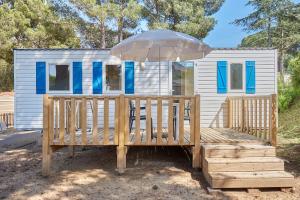 a tiny house with an umbrella and a wooden deck at Domaine Résidentiel de Plein Air Odalys La Pinède in Agde