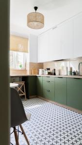 a kitchen with green cabinets and a tile floor at Przytulny apartament blisko molo Ostróda in Ostróda