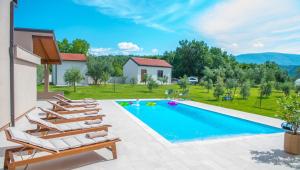 a villa with a swimming pool and lounge chairs at Holiday Home The Olive Escape in Stolac