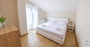 a white bedroom with a white bed and a wooden floor at Holiday Home The Olive Escape in Stolac