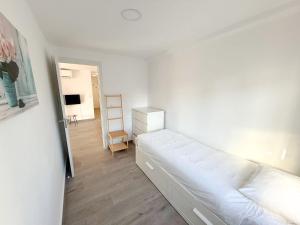 a white bedroom with a bed and a ladder at Cozy Apartment close to the center in Torremolinos