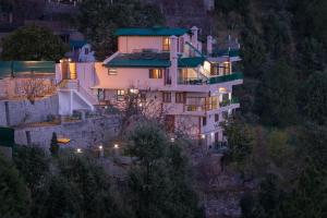 une grande maison sur le flanc d'une colline la nuit dans l'établissement Lions Den Estate 7 BD Ramgarh serviced Villa BBQ, à Rāmgarh