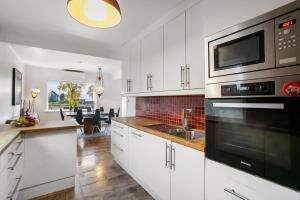 a kitchen with white cabinets and a sink and a microwave at 6 Bedroom House in Ålesund