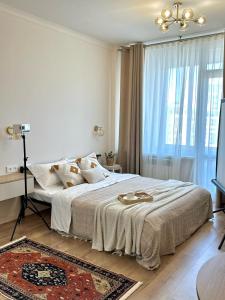 a white bedroom with a large bed with a chandelier at Apartment with a Barys projector in Gornyy Gigant