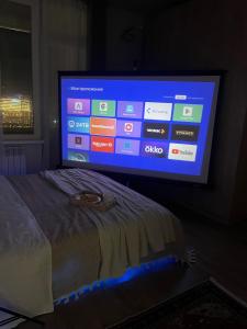 a big screen tv in a bedroom with a bed at Apartment with a Barys projector in Gornyy Gigant
