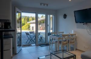 a living room with a table and chairs and a balcony at Antre de la Force in Les Paccots