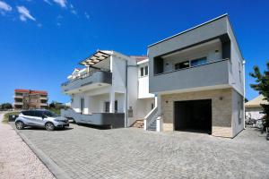 a white house with a car parked in front of it at Apartment Mia in Bibinje
