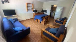 卡那封Pelican Point Waterfront Resort的客厅配有蓝色的沙发和两把椅子