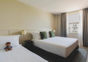 two beds in a hotel room with a teddy bear sitting between them at Gallery Hotel 4 Sup in Barcelona