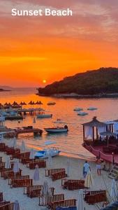 a beach with chairs and boats at sunset at Mihasi Apartments in Ksamil