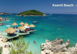 a beach with umbrellas and people in the water at Mihasi Apartments in Ksamil