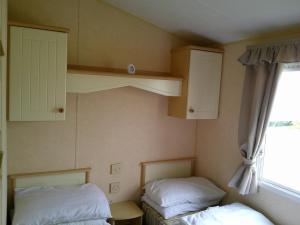 a room with two beds and cabinets and a window at Eastgate Richmond 8 Berth Blow Heated Free WIFI in Ingoldmells