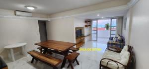 a living room with a wooden table and a dining room at Melhor apto 3 suítes vista praia à beira mar, piscinas e estruturas in Parnamirim