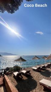 a beach with chairs and umbrellas and the ocean at Mihasi Apartments in Ksamil