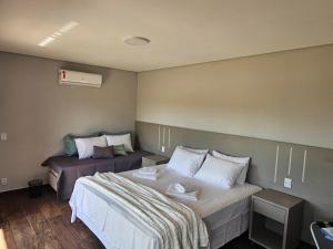 a bedroom with two beds with white sheets and a bedskirtspectspectspectspects at Pousada Vila Caminito in Brotas