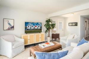 Una sala de estar con muebles blancos y un televisor. en Pier Pressure, en Greenbackville