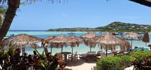 a beach with chairs and umbrellas and the ocean at Hotel Les Ondines Sur La Plage in Gustavia
