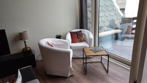 奥斯坦德Modern renovated duplex with unique and calming view T33的客厅配有白色椅子和桌子