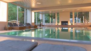 a swimming pool in a house with glass floors at Schwarzwald Wellnesshotel SAIGERHÖH I Spa Golf & Wandern über dem Titisee in Lenzkirch