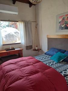 a bedroom with a bed and a desk and a window at PORTAL DE LA OVEJERIA in Tafí del Valle
