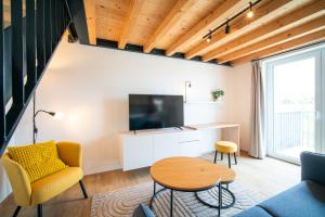 a living room with a couch and a tv and a table at Pálava Lake Apartments in Pasohlávky