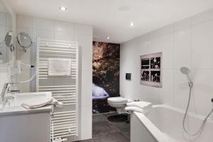 a white bathroom with a tub and a toilet at Bäuerleshütte in Breitnau +28 photos
