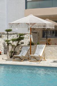 duas cadeiras e um guarda-sol junto a uma piscina em Dimitri Hotel em Himare