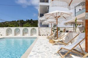uma piscina com cadeiras e guarda-sóis ao lado de um prédio em Dimitri Hotel em Himare