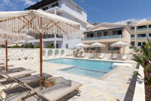 ein Pool mit Liegestühlen und Sonnenschirmen neben einem Gebäude in der Unterkunft Dimitri Hotel in Himarë