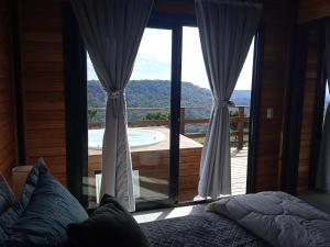 a bedroom with a bed and a view of a deck at Beautiful Cabin in the Serra Catarinense in Bocaina do Sul