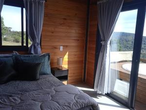 a bedroom with a bed and a large window at Beautiful Cabin in the Serra Catarinense in Bocaina do Sul