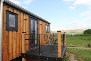 a deck of a tiny house with a table at Long Meadow Shepherd Hut - Brecon Beacons, LD3 7TD in Tal-y-llyn