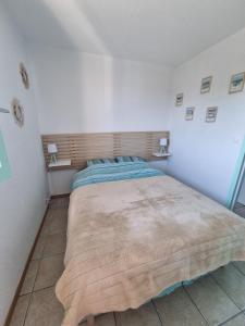 a bedroom with a large bed in a white room at Appartement cosy avec piscine chauffée ouverte du 15-06 au 15-09 in Cabourg