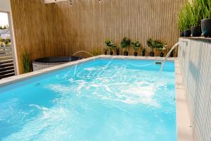 duży błękitny basen z fontanną wodną w obiekcie Domki Nord Breeze z podgrzewanym basenem i jacuzzi we Władysławowie +37 zdjęć