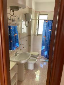baño con lavabo y aseo con cortinas azules en Dimora Vincenzo, en Gallipoli