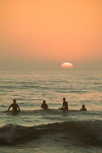 a group of people in the ocean watching the sunset at 70's Hostel in Ericeira