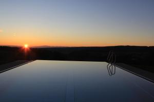 伦茨基希Schwarzwald Wellnesshotel SAIGERHÖH I Spa Golf & Wandern über dem Titisee的从游泳池欣赏日落美景