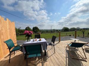 einen Tisch mit Stühlen und eine Vase mit Blumen auf einer Terrasse in der Unterkunft Les petites maisons dans la monterie - Le Jardin - in Saint Lo