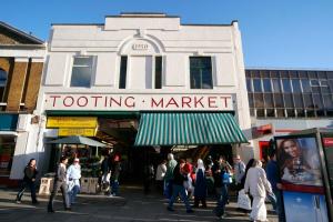 a group of people walking in front of a market at Tooting Stays in London