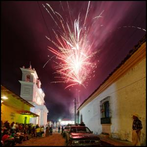 un fuego artificial que explota en el cielo sobre una calle en Los Almendros de San Lorenzo, en Suchitoto