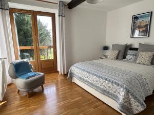 una camera da letto con un letto, una sedia e una finestra di Les Deux Chevaux Chambres d’Hôtes a Rouvenac