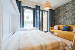 a bedroom with a large bed and a yellow couch at Laguna Beskidów Resort - Studio Individual in Zarzecze