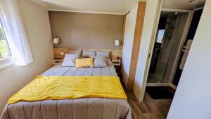 Un dormitorio con una cama grande con una manta amarilla. en Les petites maisons dans la Monterie La Source, en Saint Lo